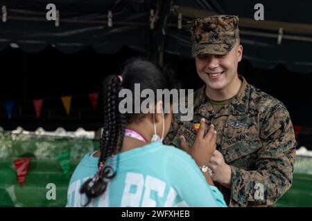 Corpsman 2nd Class Jackson Hollund mit dem 9th Engineer Support Battalion, 3rd Marine Logistics Group, überreicht einem thailändischen Kind während einer Veranstaltung zum Kindertag im Hauptquartier der Royal Thai Armed Forces, Bangkok, Thailand, 13. Januar 2024 Süßigkeiten. Mitglieder des Teams für humanitäre Minenaktionen wurden eingeladen, an der jährlichen Veranstaltung zum Kindertag in Thailand teilzunehmen, um Kindern zu gedenken und das Bewusstsein für das wohl von Kindern und ihre Rechte zu schärfen. Stockfoto
