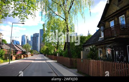 Vilnius (Litauen) - Giedraiciu Straße. Gentrifizierungskonzept. Alte Holzgebäude im Vordergrund vs. Moderne Wolkenkratzer im Hintergrund Stockfoto