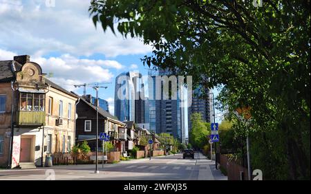 Vilnius (Litauen) - Giedraiciu Straße. Gentrifizierungskonzept. Alte Holzgebäude im Vordergrund vs. Moderne Wolkenkratzer im Hintergrund Stockfoto