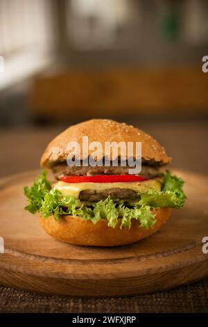 Rindfleischburger auf Holzplatte leckerer Burger, großer Burger, ungesunde Kalorien Mahlzeit Stockfoto
