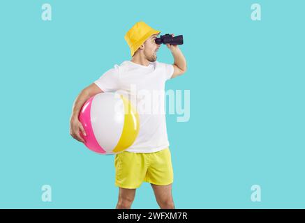 Lustiger schockierter Mann in Strandkleidung, der durch ein Fernglas schaut, findet ein Schnäppchenangebot für Sommerausflüge. Stockfoto