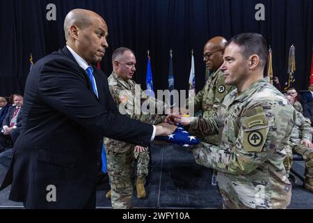 US-Senator Cory A. Booker links und Brig. General Robert W. Hughes, Jr., zweiter von links, Assistant Adjutant General – Army, überreicht Oberst Timothy P. Sorrentino, rechts, Commander, amerikanische und New Jersey-Flaggen. Major Donald Chapman Jr., 1. Bataillon, 114. Infanterieregiment und Alpha-Kompanie, 2. Bataillon, 113. Infanterieregiment, 44. Infanterieregiment, New Jersey Army National Guard, während der Abschiedszeremonie des 44. IBCT in der Cure Insurance Arena, Trenton, New Jersey, 14. Januar 2024. Mehr als 1.500 NJARNG-Soldaten werden zur Unterstützung der U.S. Central Co. Eingesetzt Stockfoto