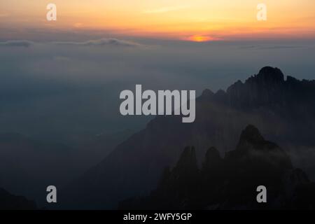 Eine goldene Sonne sinkt unter dem Horizont in der White Cloud Scenic Area, vom Turtle Peak in den Huangshan Yellow Mountains aus gesehen. Stockfoto