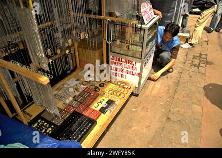 Ein Käufer bereitet seinen Verkaufsstand mit alten (abgezogenen, abgelaufenen) indonesischen Banknoten vor, die als Sammlerstücke verkauft werden. Dieser befindet sich neben einem Schmuckstand auf einem Straßenmarkt in Jatinegara, Ost-Jakarta, Jakarta, Indonesien. Stockfoto