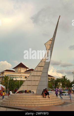 Die Menschen haben Freizeit an und um eines der beiden identischen Denkmäler, die als Eingangstor zum Pantai Losari (Losari Beach, ein beliebtes Erholungsziel für Sonnenuntergänge in Makassar City, Süd-Sulawesi, Indonesien. Stockfoto