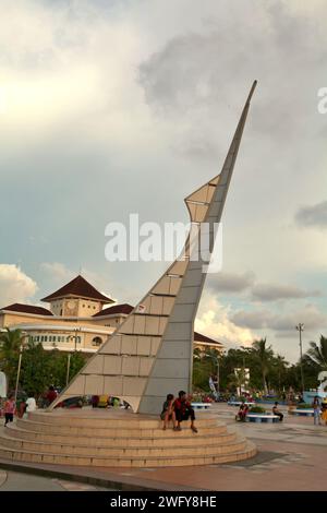 Die Menschen haben Freizeit an und um eines der beiden identischen Denkmäler, die als Eingangstor zum Pantai Losari (Losari Beach, ein beliebtes Erholungsziel für Sonnenuntergänge in Makassar City, Süd-Sulawesi, Indonesien. Stockfoto