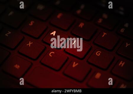 Die Tastatur wird mit rotem Licht beleuchtet, das die Buchstaben A i (Nahaufnahme) hervorhebt Stockfoto