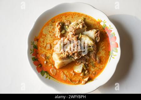 Lontong Sayur oder Gemüsereis Kuchen ist ein typisches indonesisches Essen auf einer weißen Platte mit isoliertem weißem Hintergrund Stockfoto