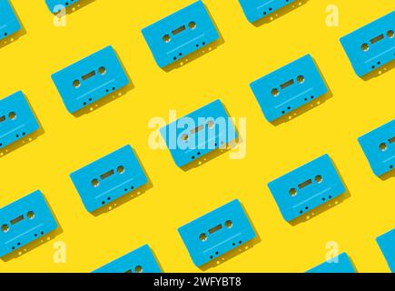 Muster mit blauen Retro-Audiokassetten auf gelbem Hintergrund. Kreatives Konzept der Retro-Technologie. Ästhetik der 80er Jahre. Vintage-Audio Stockfoto