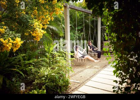 Mutter und Tochter genießen am Nachmittag den Schaukelstuhl im wunderschönen gemütlichen Garten Stockfoto