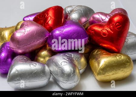 Bunte herzförmige Pralinen auf weißem Hintergrund. Nahaufnahme. St. Valentinstag-Konzept. Stockfoto