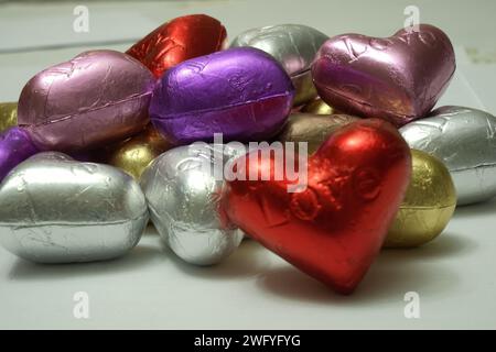 Bunte herzförmige Pralinen auf weißem Hintergrund. Nahaufnahme. St. Valentinstag-Konzept. Stockfoto