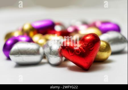 Bunte herzförmige Pralinen auf weißem Hintergrund. Nahaufnahme. St. Valentinstag-Konzept. Stockfoto