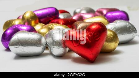 Bunte herzförmige Pralinen auf weißem Hintergrund. Nahaufnahme. St. Valentinstag-Konzept. Stockfoto