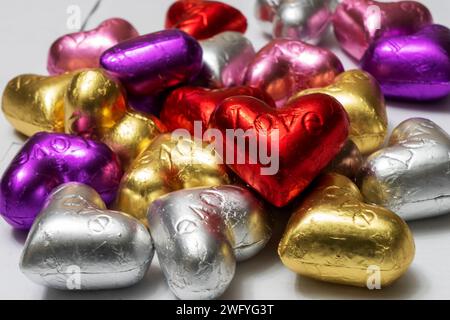 Bunte herzförmige Pralinen auf weißem Hintergrund. Nahaufnahme. St. Valentinstag-Konzept. Stockfoto