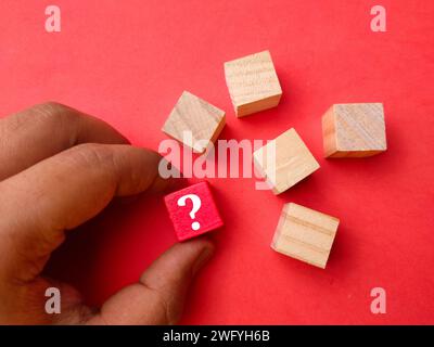 Holzblock mit Symbolfrage auf rotem Hintergrund mit Draufsicht. Stockfoto