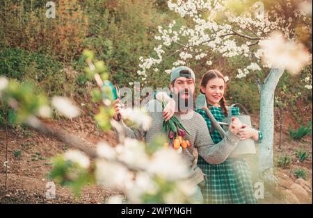 Gärtner-Paar im Garten. Glückliche Gärtner mit Frühlingsblumen Stockfoto