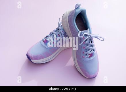 Violette blaue sportliche Laufschuhe für Frauen auf rosa Hintergrund. Mode, Trainingsschuhe für Workout, Fitnessstudio, Schuhe für Damen. Nationalschuh Der Welt Stockfoto