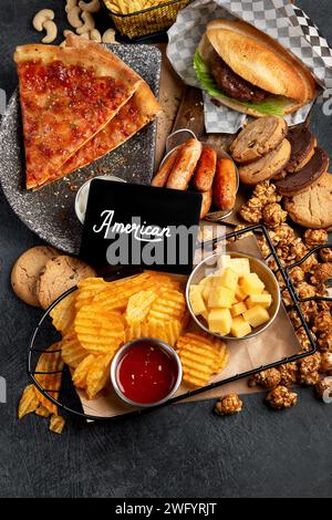Fastfood auf dunklem Hintergrund. Junk Food für Herz und Haut. TRANS FAT-Konzept. Draufsicht Stockfoto