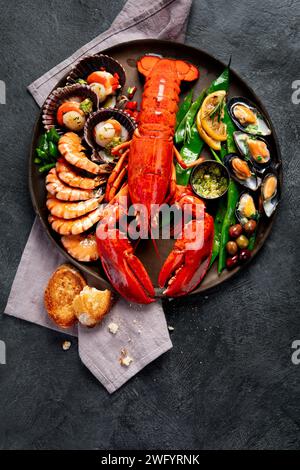 Großer roter Hummer auf Teller mit Garnelen und Muscheln mit Zitrone, Souce Pesto und Brot. Meeresfrüchte-Konzept. Draufsicht. Stockfoto