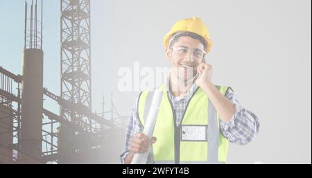 Bild eines männlichen kaukasischen Architekten mit Telefon und Plänen über der Baustelle Stockfoto