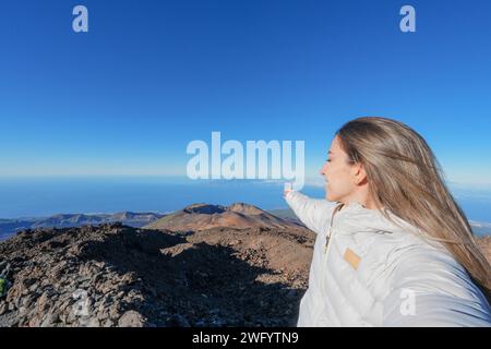 Auf Teneriffa steht eine Frau auf dem Gipfel des Teide und zeigt in Richtung Himmel. Stockfoto