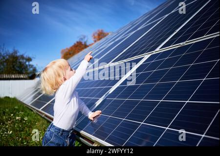 Kleines Kind, das sich große Solarpaneele ansieht. Interessierter Junge untersucht, wie Solarbatterien funktionieren. Kleiner Junge, der auf ein neues Panel zeigt. Kinderkonzept und Investitionen in erneuerbare Energien. Stockfoto