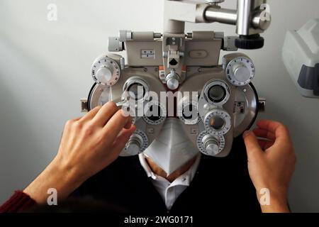 Ein Augenarzt, der die Augen eines Patienten in einer Arztpraxis untersucht Stockfoto