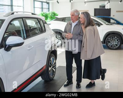 Ein älteres kaukasisches Paar wählt ein neues Auto in einem Autohändler. Stockfoto