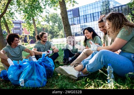Multiethnische Gruppe von Freiwilligen, die sich nach der Reinigung des Stadtparks ausruhen. Stockfoto