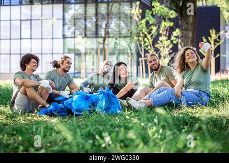 Multiethnische Gruppe von Freiwilligen, die sich nach der Reinigung des Stadtparks ausruhen. Stockfoto