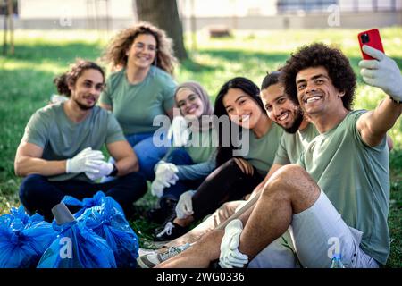 Multiethnische Gruppe von Freiwilligen, die sich nach der Reinigung des Stadtparks ausruhen. Stockfoto