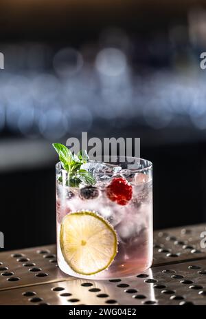 Pink Cocktail Gin Tonic Drink mit Himbeeren, Heidelbeeren, Limette und frischer Minze. Stockfoto