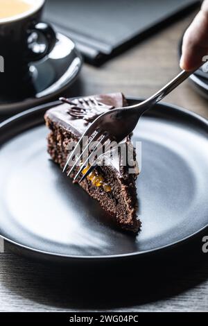 Ein Gast in einem Café schneidet einen Sacherkuchen mit einer Gabel. Stockfoto