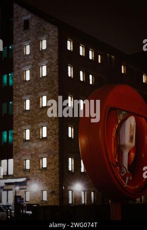 Ein lebensrettender Ring vor den beleuchteten Apartments an den historischen Docks von Gloucester bei Nacht im Winter Stockfoto