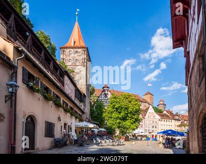 Blick auf den Tiergärtnertorturm in Nürnberg, ein befestigter Turm in der mittelalterlichen Stadt, mit Straßencafés auf dem Tiergärtnertorplatz. Stockfoto