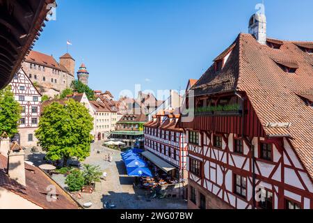 Der Tiergärtnertorplatz in Nürnberg ist gesäumt von Fachwerkhäusern und Straßencafés, über denen die Türme der Burg blicken. Stockfoto