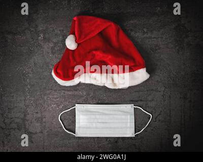 Santa Claus Hut und medizinische Maske direkt oben gesehen. Quarantäne während des Weihnachtsferien-Konzepts. Stockfoto