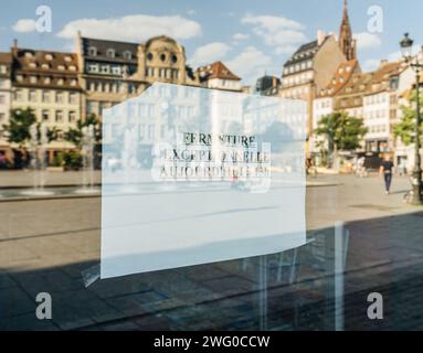 Reflexion eines Stadtplatzes und von Gebäuden auf einem unerwarteten Schließungsschild auf Französisch. Stockfoto