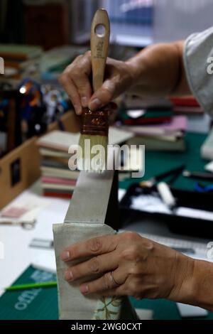 Eine Hand, die einen Pinsel in der Nähe eines Farbtubus hält Stockfoto