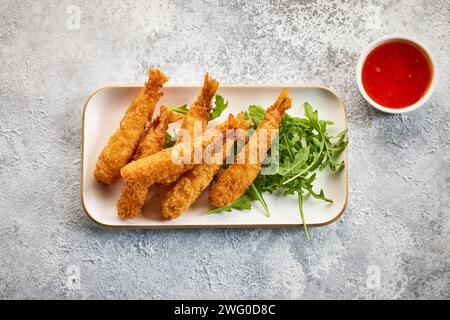 Platte mit panierten Torpedo-Garnelen auf grauem Hintergrund gestrichenem Küchentisch, Blick von oben Stockfoto