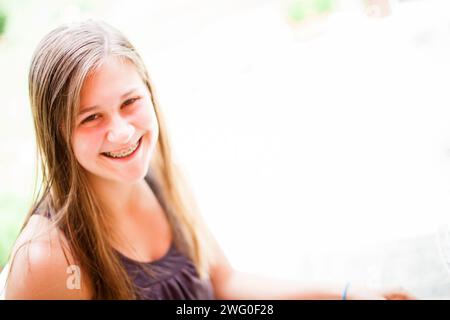 Ein 16-jähriges Mädchen lächelt, während es draußen sitzt. Stockfoto