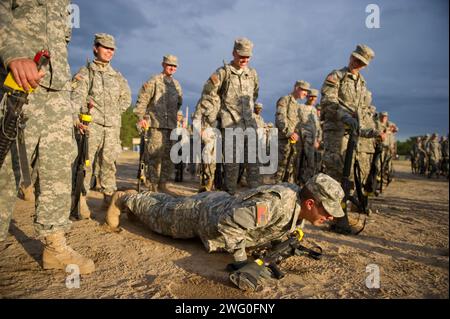 Nachdem er von seinem Drill-Sergeant angeschrien wurde, macht ein Soldat Liegestütze, während sein Gewehr sicher auf seinen Händen liegt. Stockfoto