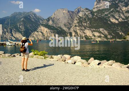 Weibliche Touristen fotografieren Windsurfer am Gardasee. 15. August 2023 Nago - Torbole, Italien Stockfoto