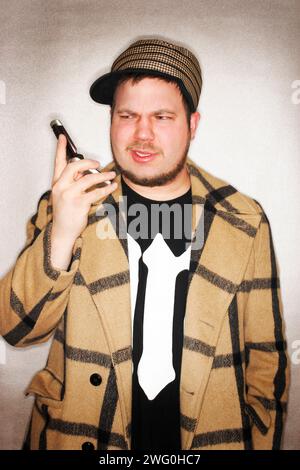 Ein junger, hipper Mann mit seinem Handy und einem verärgerten Blick im Gesicht. Stockfoto