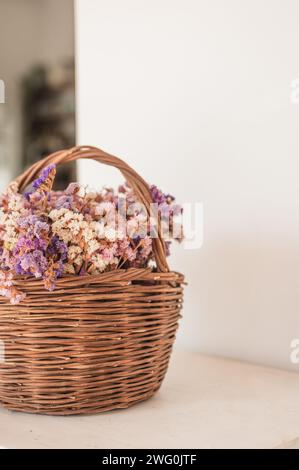 Buntes getrocknetes Blumenarrangement in gewebtem Korb auf weißem Hintergrund Stockfoto