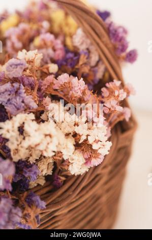 Nahaufnahme der bunten Statice Blumen (Limonium) in einem gewebten Korb Stockfoto