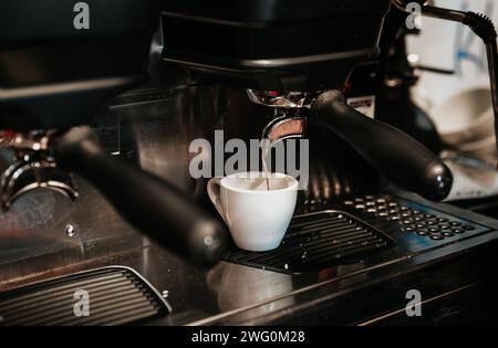Nahaufnahme einer Espressomaschine, die frischen schwarzen Kaffee in die Tasse gießt Stockfoto