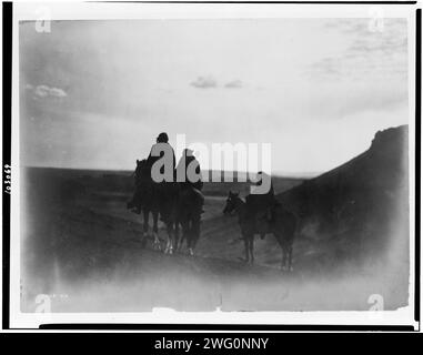 Unter den Black Buttes-Navaho Land, um 1905. Drei Navaho-Indianer zu Pferd, silbrig auf schwarzen Hintern, im Abendlicht. Stockfoto