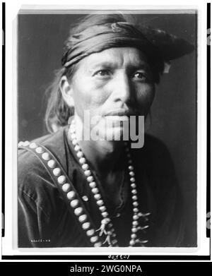 Der weiße Sänger, 1906. Kopf-und-Schultern-Porträt des Navajo-Mannes, leicht nach rechts gerichtet, mit Stirnband und silberner Kürbisblütenkette. Stockfoto